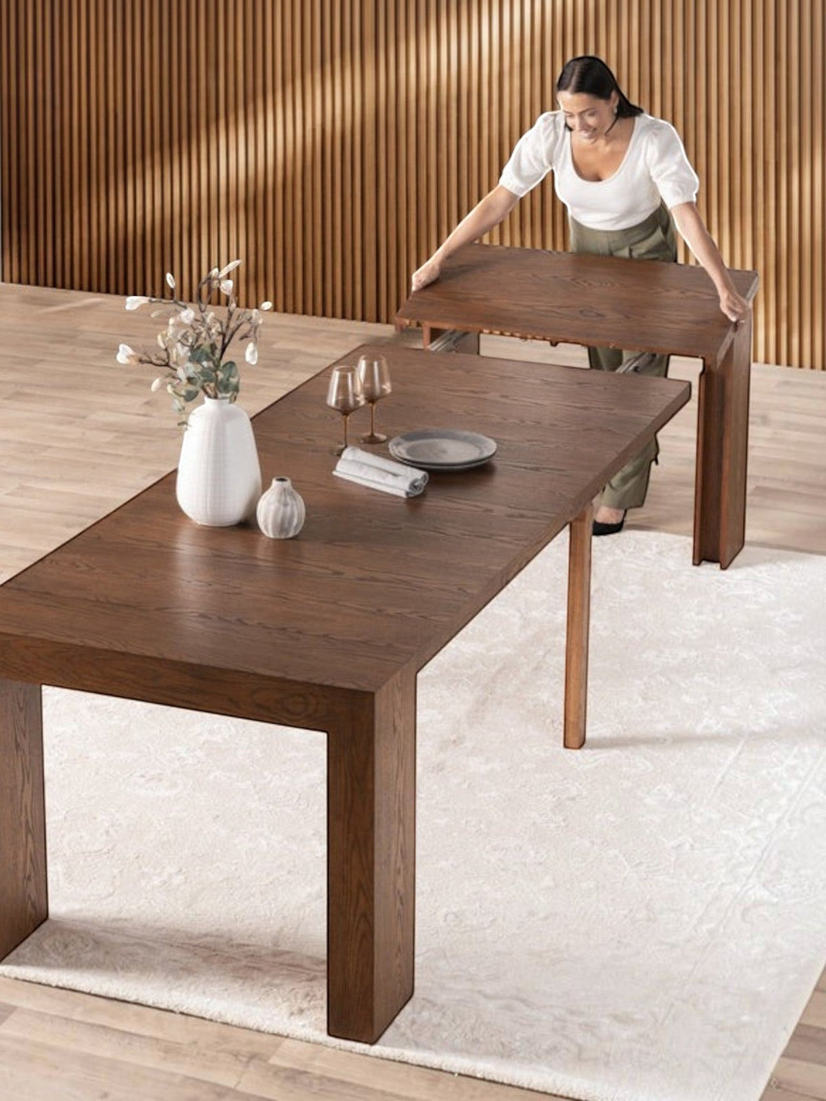 Femme installant une rallonge sur la table de salle à manger extensible en noyer américain TOCO Meubles