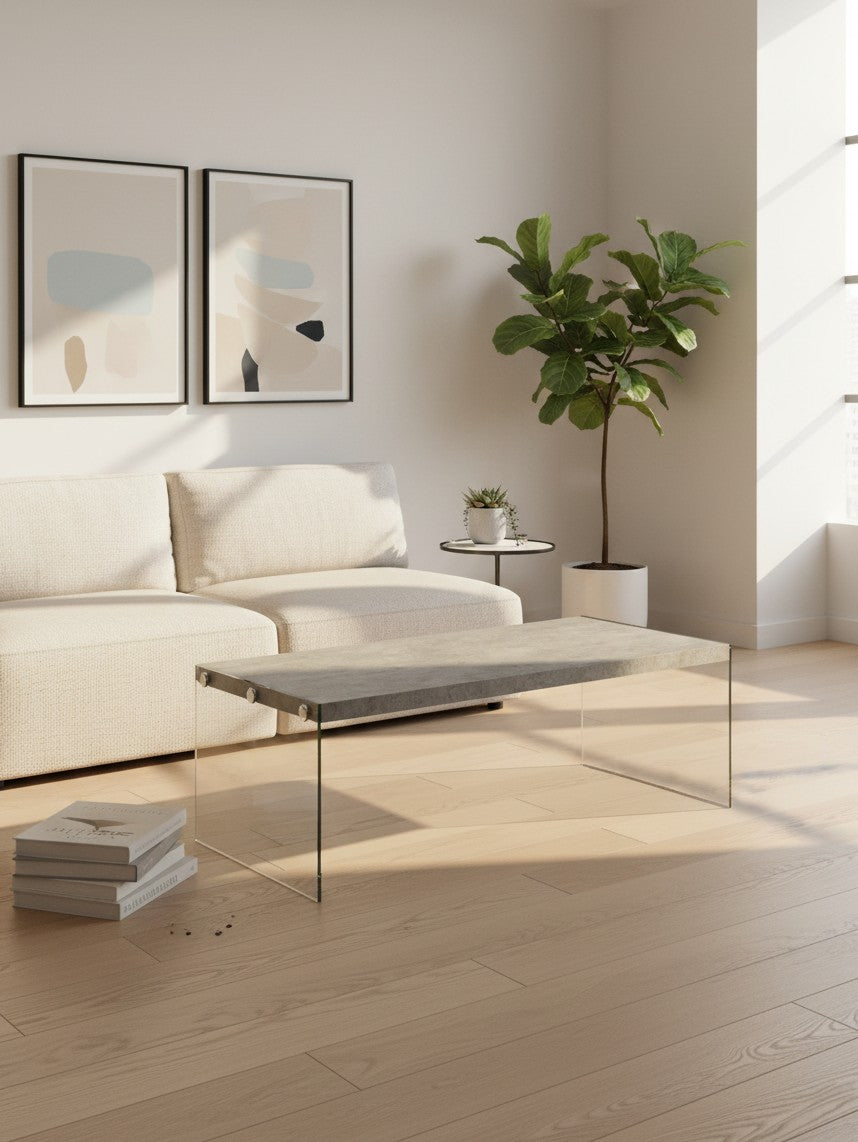 Table de salon Zaki TOCO Meubles avec plateau effet béton et pieds en verre trempé transparent dans un salon moderne