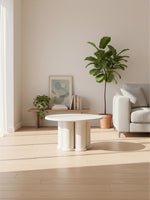 Table de salon ronde Harmonie par TOCO Meubles avec base cylindrique en bois clair dans un salon moderne