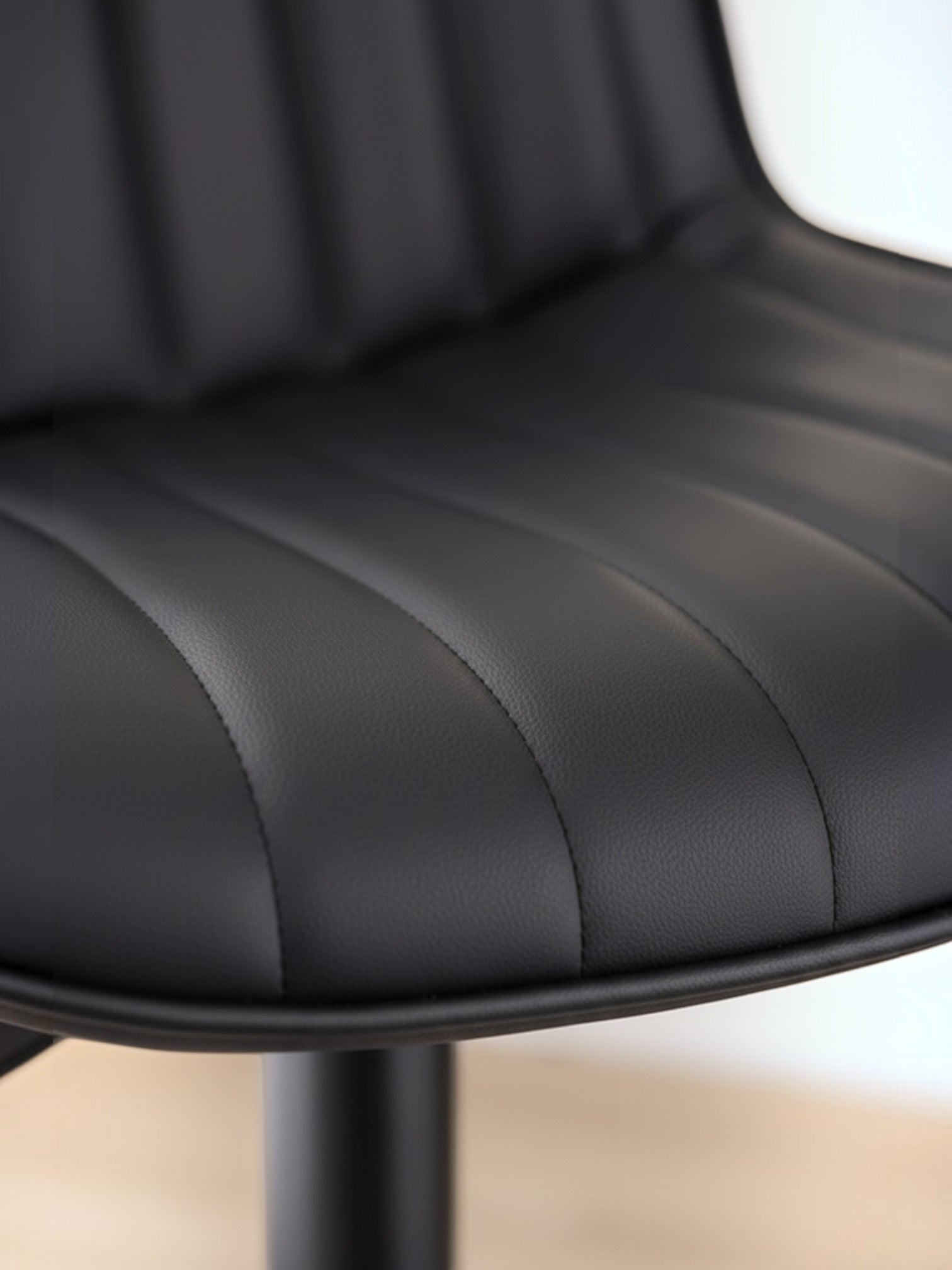 Gros plan sur le revêtement en PU noir du tabouret de bar Ali par TOCO Meubles avec ses coutures verticales élégantes.