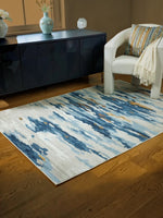 Tapis Vinlett par TOCO Meubles au motif abstrait bleu, gris et beige, lavable en machine sur un plancher en bois.