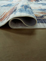 Tapis Vinlett de TOCO Meubles avec motif abstrait dans des tons bleus, gris et orangés, lavable en machine