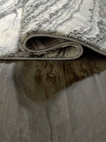 Tapis Wysdale de TOCO Meubles avec motif agate gris et blanc, texture tissée effet haut-bas sur sol en bois
