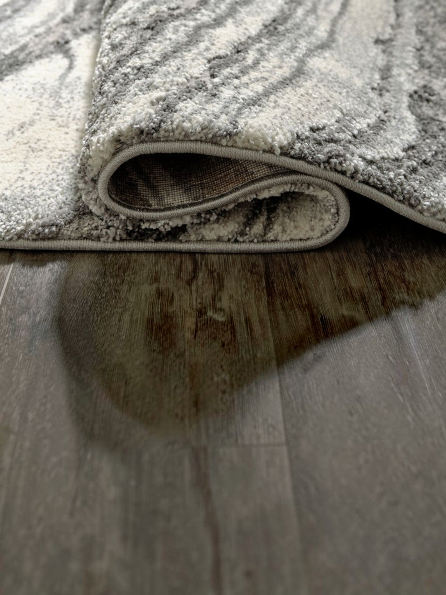 Tapis Wysdale de TOCO Meubles avec motif agate gris et blanc, texture tissée effet haut-bas sur sol en bois