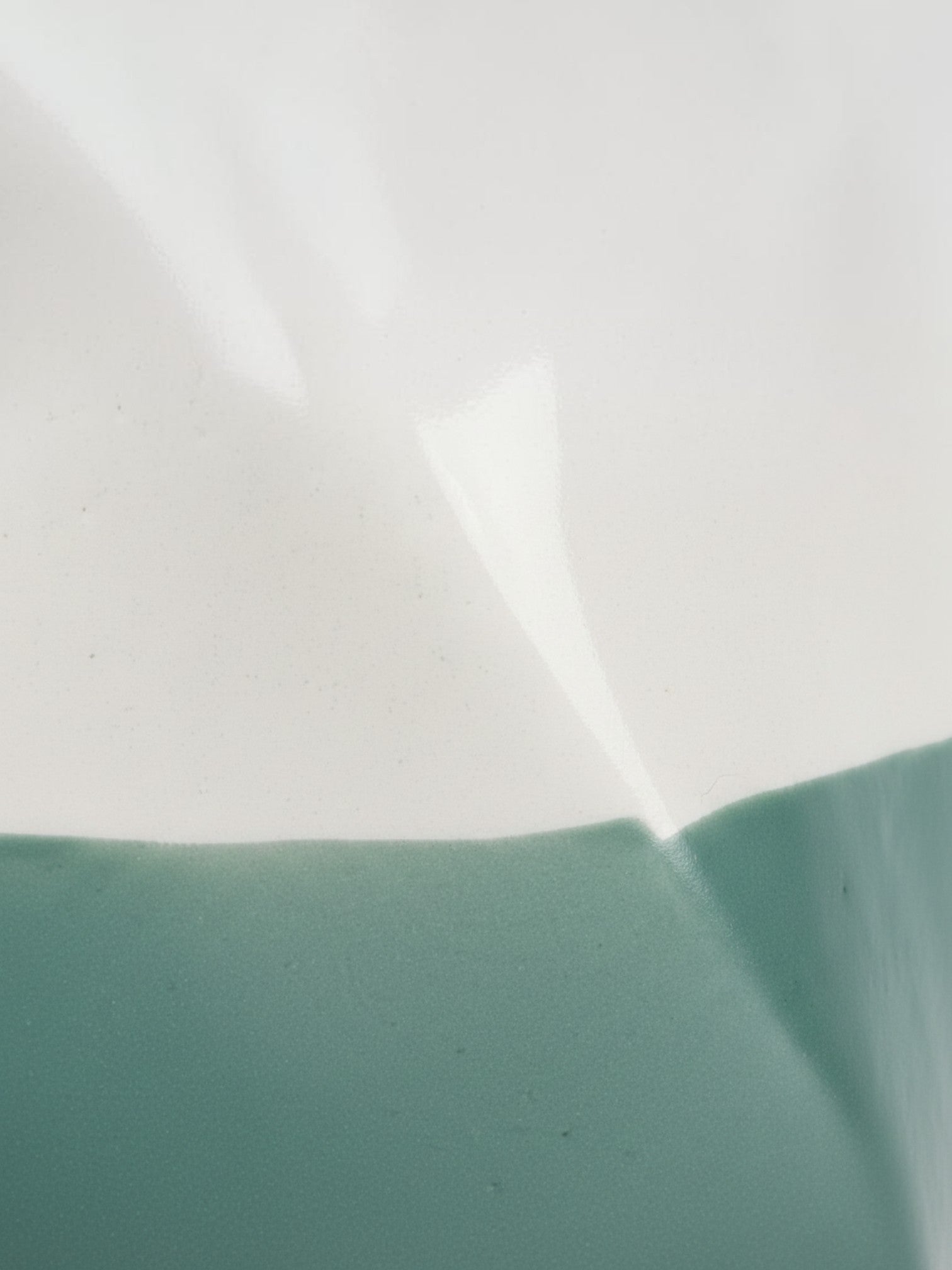 Gros plan sur la texture bicolore blanc et vert sauge du vase en céramique Tethys de TOCO Meubles