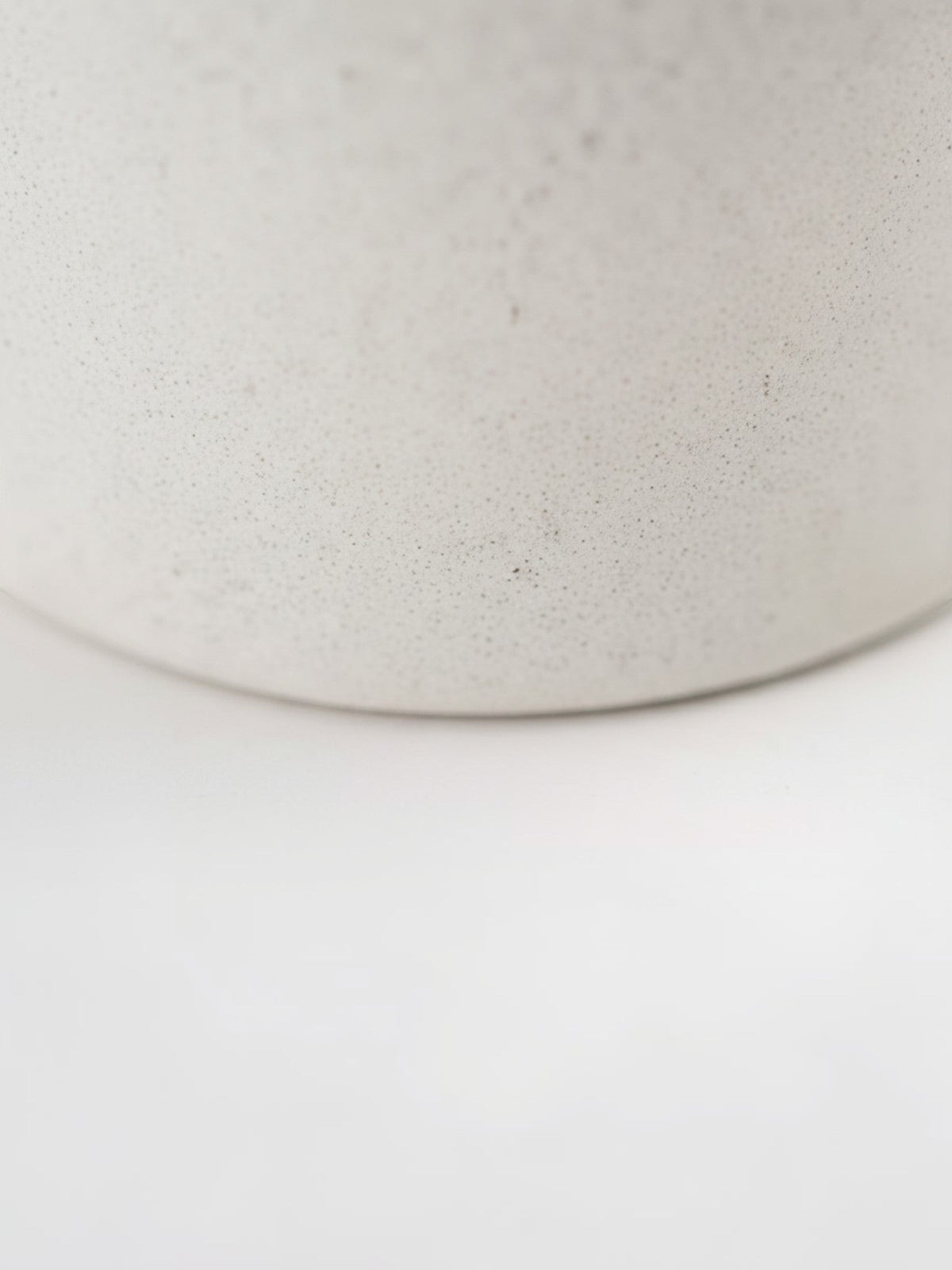 Gros plan sur la texture mate et granuleuse du petit vase en céramique blanche Burton de TOCO Meubles