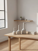 Trois vases Burton en céramique blanche mate de TOCO Meubles disposés sur une table en bois clair